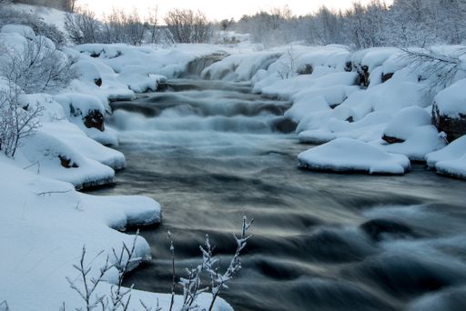 A waterfall flowing over the stones on a cold snowy winter day in Iceland