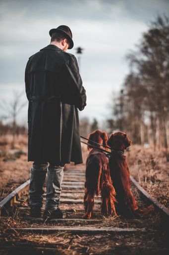 A vertical shot of a Swedish man with a cocker spaniel standing on a railway.