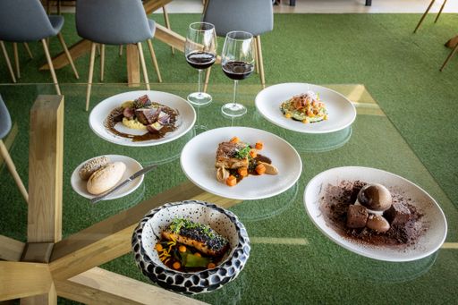 Some different delicious dishes and desserts with two glasses of red wine on the table.