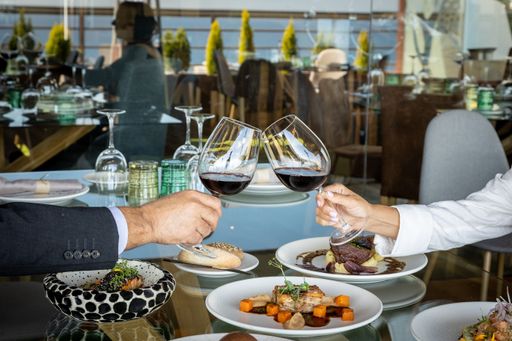 A couple clinking two glasses of wine in a restaurant.