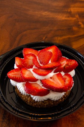 A closeup of a cake with strawberries and cream on top
