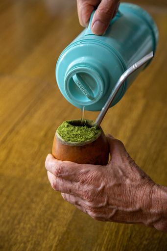Hands of an old man making the traditional South American drink yerba mate in a gourd