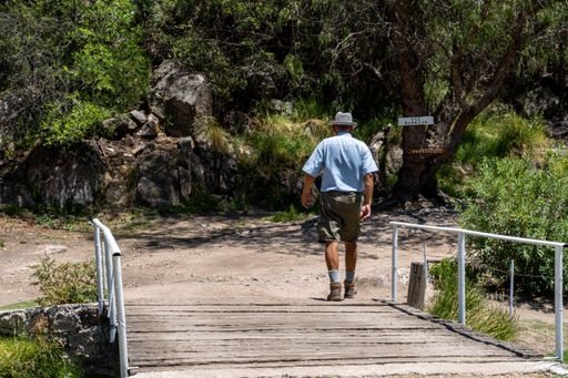 A Caucasian old man walking on the pathway on a sunny day