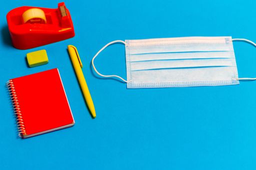 A high angle shot of a medical mask and stationary on a blue background