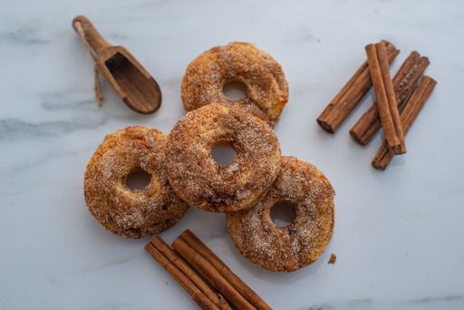 A top view of brown donuts and cinnamon sticks placed on the marble table