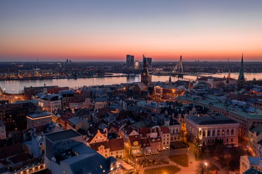 A beautiful cityscape of Riga surrounded by lights during the sunset in the evening in Latvia