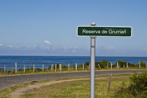 A green signboard with writing "Reserva de Grumari" on the highway next to the sea