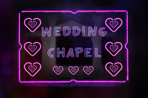 A neon wedding chapel sign in rainy window