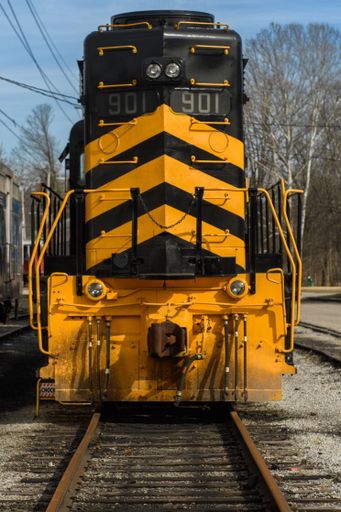 The old rusty train locomotive with yellow signs on its front in the park