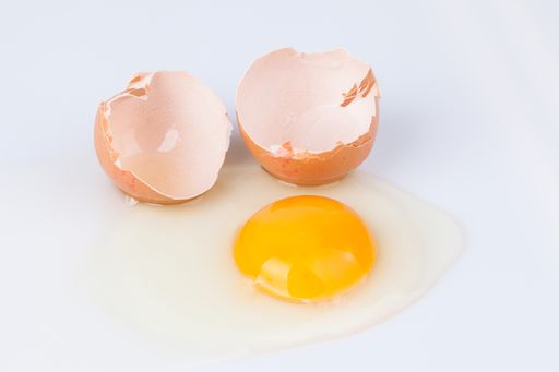 A closeup shot of a cracked  chicken egg isolated on a white background