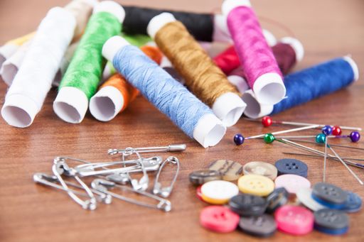 A closeup shot of colorful yarn and needles for sewing on a wooden surface
