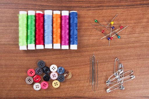 A closeup shot of colorful yarn and neeldes for sewing on a wooden surface