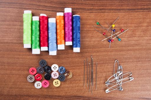 A closeup shot of colorful yarn and neeldes for sewing on a wooden surface