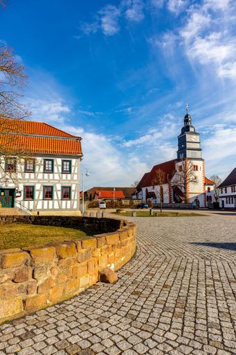 A vertical shot of a house and a church on a sunny day in Breitungen, Germany