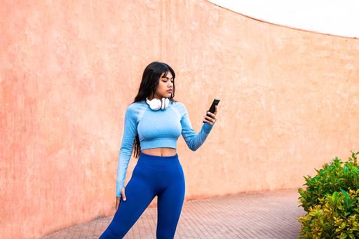 AAttractive Colombian woman using her mobile phone while playing sports in a park