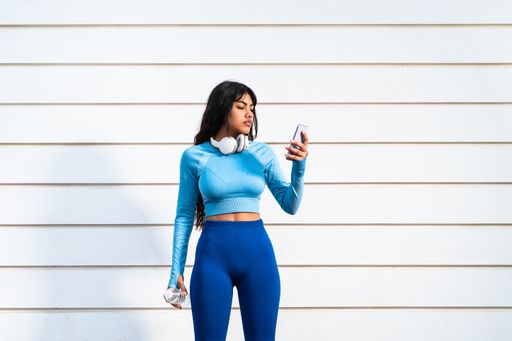 AAttractive Colombian woman using her mobile phone while playing sports in a park