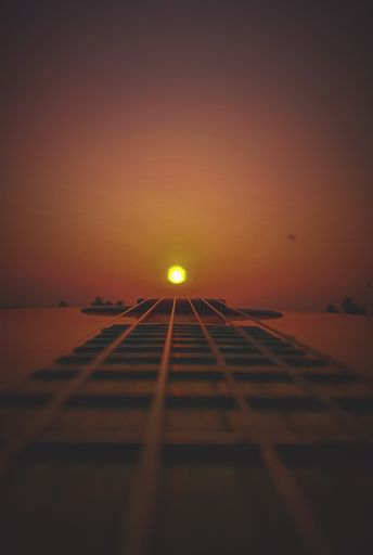 A vertical shot of guitar strings with golden sunset background