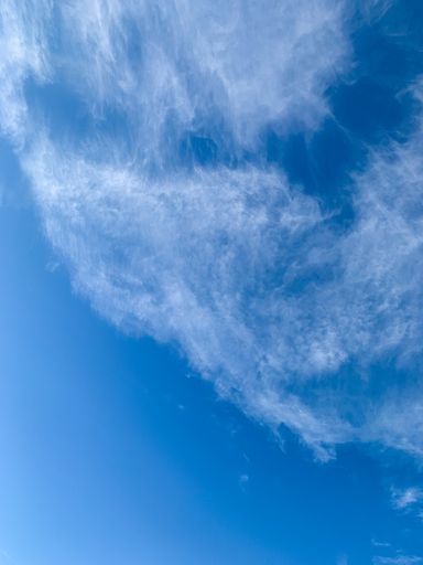 A vertical shot of clouds against the bright blue sky on a sunny day