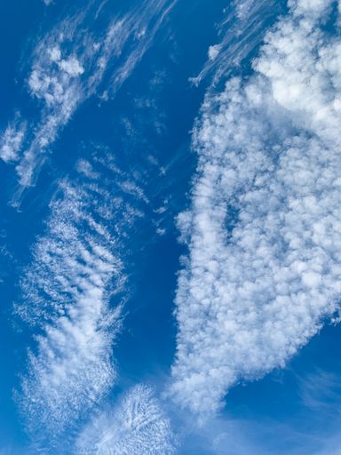 A vertical shot of clouds against the bright blue sky on a sunny day