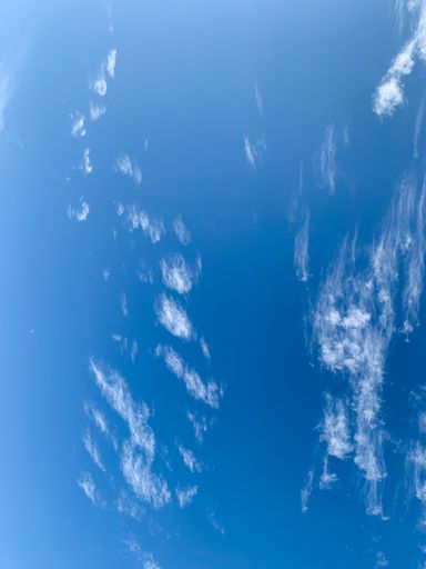 A vertical shot of clouds against the bright blue sky on a sunny day