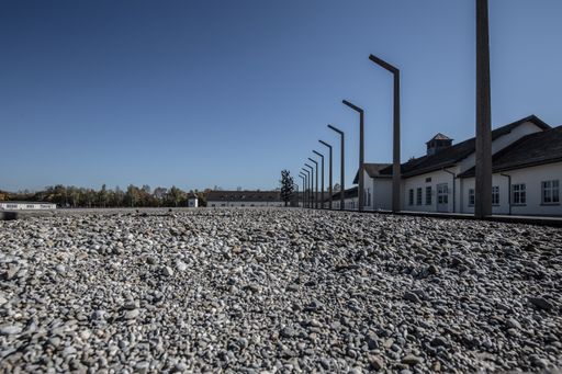 A low angle shot of a gravel ground with houses and crooked poles aligned on the left
