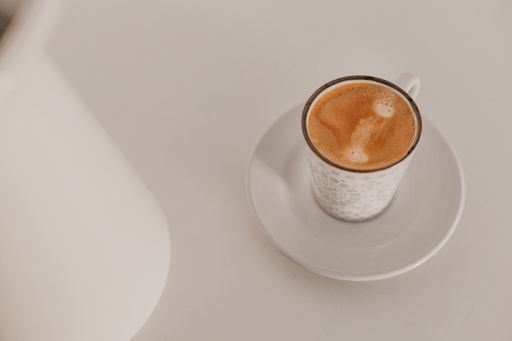 A high angle shot of a white cup of cappuccino on a white background