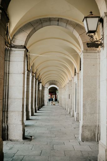A vertical shot of people walking through an arcade corridor in Madrid, Spain