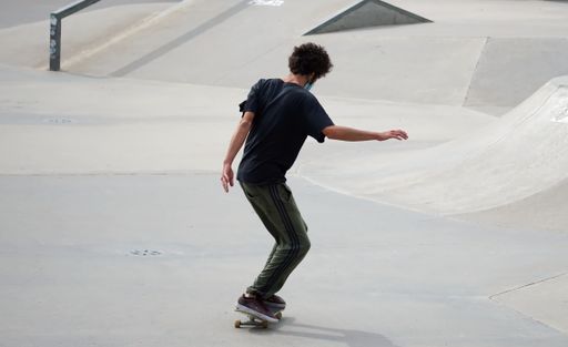 A young male wearing a facemask and skating in a skatepark - the new normal