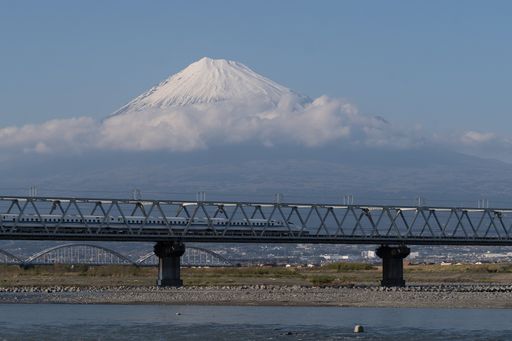 A breathtaking shot of the high-speed Shinkansen train over Fuji river with a mesmerizing Fuji mountain on the background