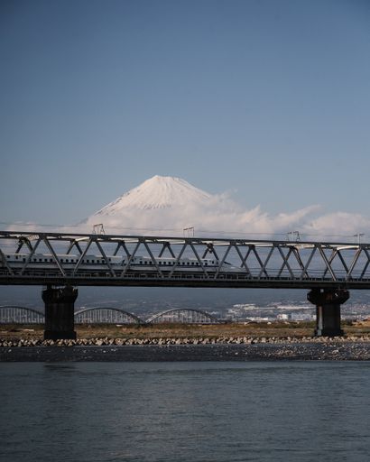 A breathtaking shot of the high-speed Shinkansen train over Fuji river with a mesmerizing Fuji mountain on the background