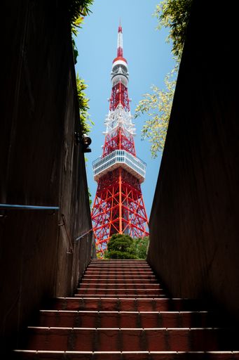 A low angle shot of the mesmerizing Tokyo tower with a staircase on the foreground