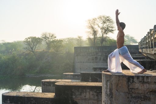 A closeup of a young boy performing yoga early in the morning while wearing a dhoti