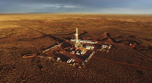 An aerial shot of hydraulic fracturing equipment on a brown field