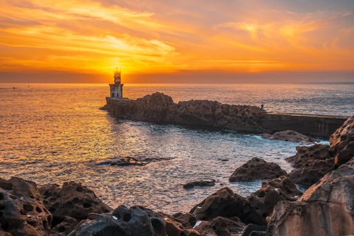 A lighthouse during a beautiful orange sunset in the Pasajes San Juan, Gipuzkoa, Spain