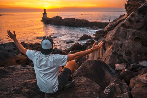 A young man near the lighthouse during a beautiful orange sunset in the Pasajes San Juan, Gipuzkoa, Spain