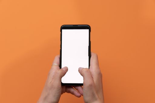 A closeup shot of male hands using a smartphone on an orange background