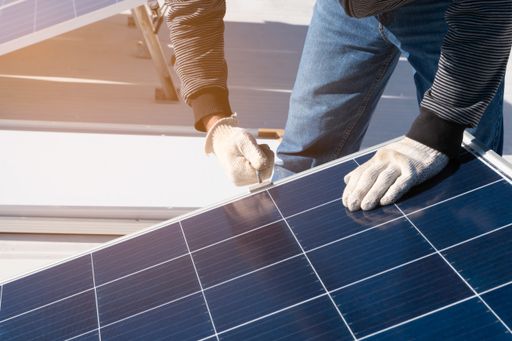 A high angle shot of a male working on adjusting solar panels on a roof