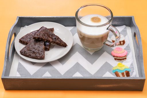 A closeup shot of breakfast - chocolate cake and a glass of coffee in a tray