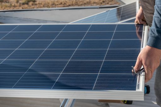 A selective focus shot of a worker installing solar panel