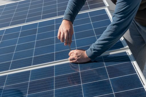 A high angle shot of a male working on adjusting solar panels on a roof