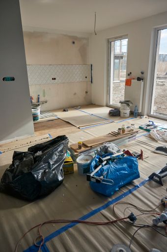 A vertical shot of various tools laying on the floor in a living room under renovation of an apartment building