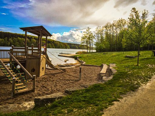 A closeup of a small wooden playground near the lake shore on a sunny day