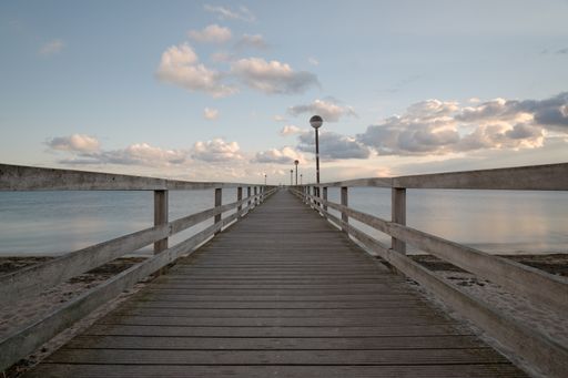 A wooden dock in the lake with a cloudy sky