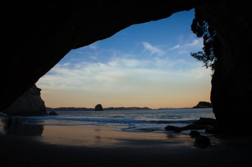 A beautiful view of a beach from a cave at sunset