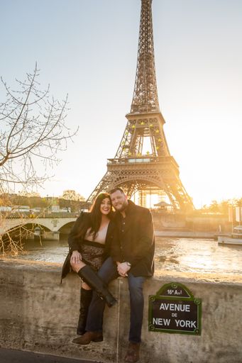 A vertical shot of the happy couple taking pictures with Eiffel Tower on the background, Paris, France