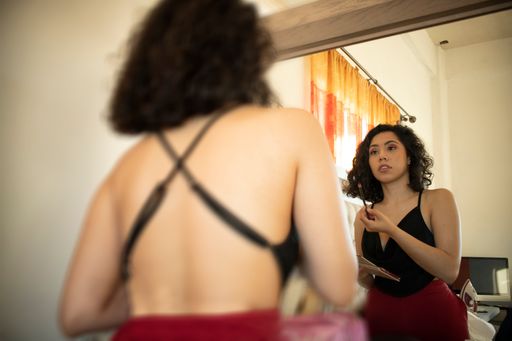 A young Hispanic female applying makeup in front of a mirror