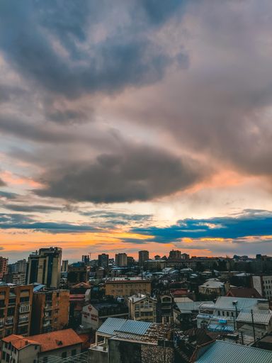 A shot of cityscape under cloudy sky during sunset