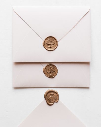 A closeup of wedding envelopes with wax seals on a white background