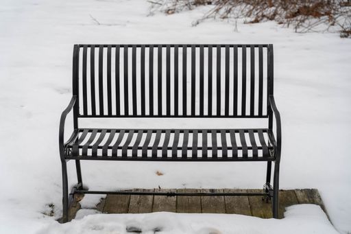 A shot of small metal bench in a snowy park