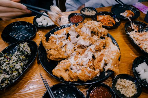 A high angle shot of a plate of fried chicken and bowls of different dressings and sauces on a table